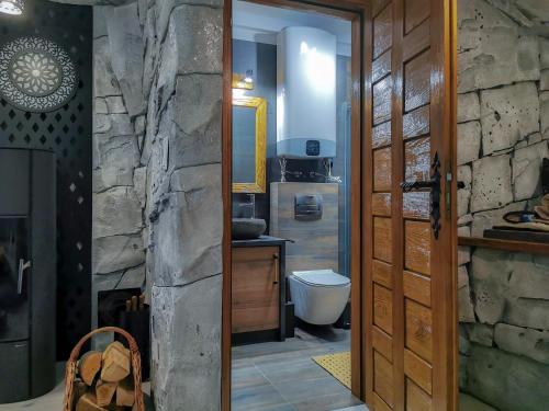 a bathroom with a toilet and a stone wall at Pienińska Grota - z Kominkiem i Basenem - przy Wyciągu in Szczawnica