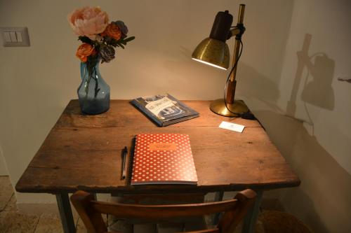 a desk with a lamp and a book and a vase of flowers at Lumè in Putignano