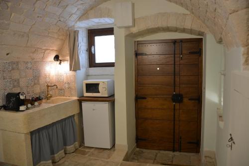 a kitchen with a sink and a door with a microwave at Lumè in Putignano