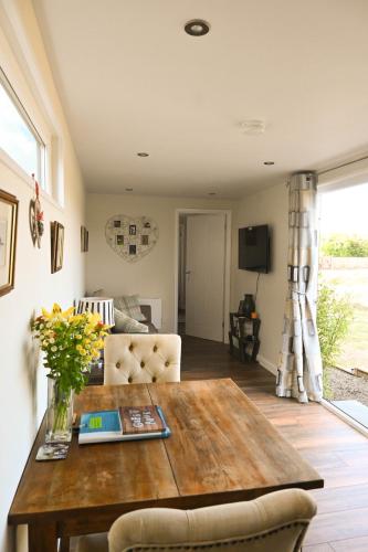 a living room with a wooden table and a couch at Sweet Pea Cabin in Badsey