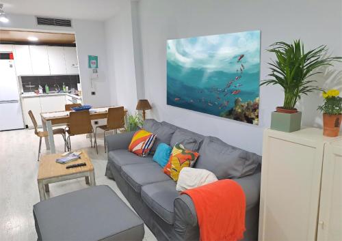 een woonkamer met een grijze bank en kleurrijke kussens bij La Casa de Koko in Las Palmas de Gran Canaria