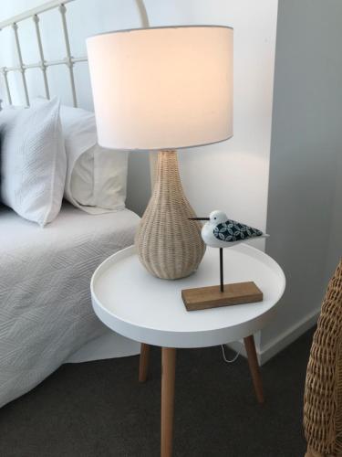 a lamp on a table next to a bed at Beachfront Retreat - Ducted Air - Free Wifi in Coffs Harbour
