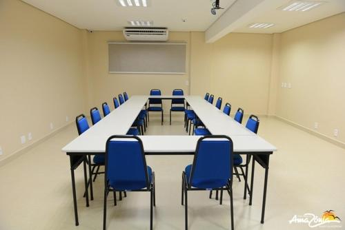 a conference room with a long table and blue chairs at Hotel Portal da Amazônia in Várzea Grande