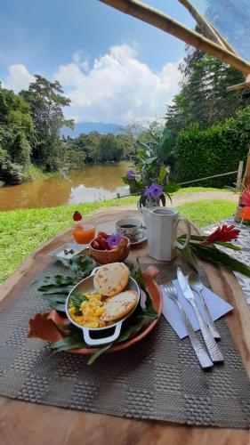 una mesa de desayuno con un plato de comida y un río en Aguas Claras Bamboo Ecolodge en Guaduas