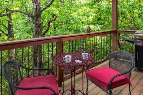 a patio with two chairs and a table on a deck at Eureka Sunset Cabins in Eureka Springs