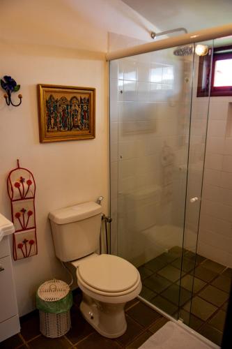 a bathroom with a toilet and a glass shower at Aconchego Itaipava in Petrópolis
