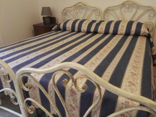 Cama blanca con edredón de rayas azul y blanco en Villa Sacro Cuore, en San Giovanni Rotondo