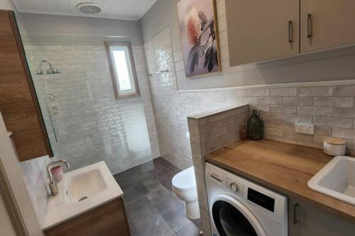 ein Badezimmer mit Waschbecken und Waschmaschine in der Unterkunft 'Pickett's Cottage' - Circa 1868 - Oldest in Knox! in Boronia