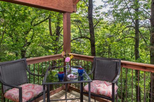 a table and two chairs on a deck with trees at Eureka Sunset Cabins in Eureka Springs