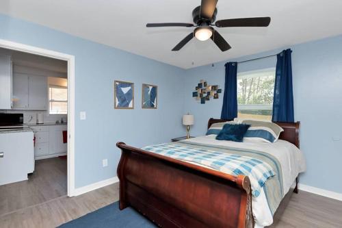 a bedroom with a bed with blue walls and a ceiling fan at Adorable Blue Little House in Charleston