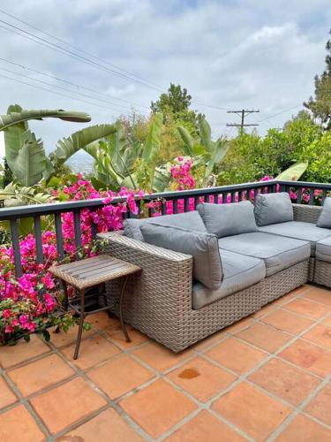 a wicker couch sitting on a patio with flowers at Entire villa on Sunset Strip in Los Angeles
