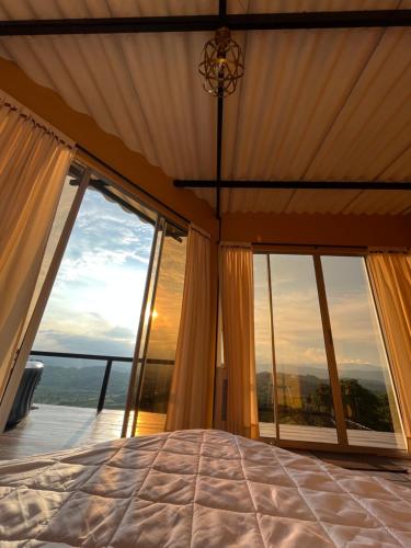 a bedroom with a bed and large windows at La Paloma Glamping in Palestina
