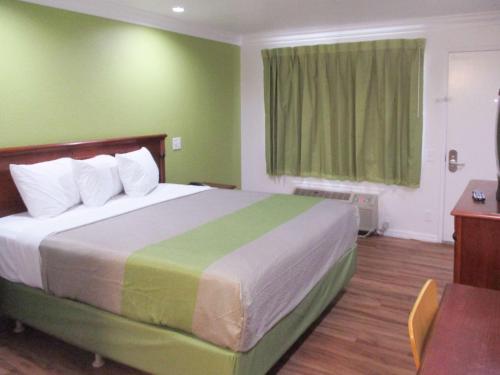 1 dormitorio con 1 cama grande y paredes verdes en Motel 6-Fresno, CA, en Fresno