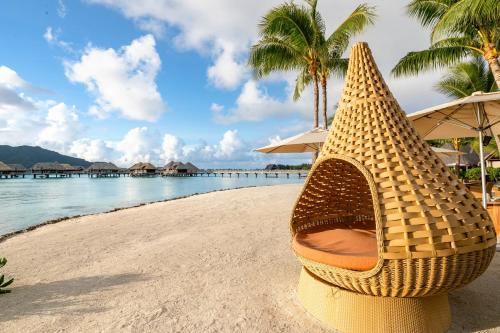 a chair on the beach next to the ocean at InterContinental Bora Bora & Thalasso Spa, an IHG Hotel in Bora Bora