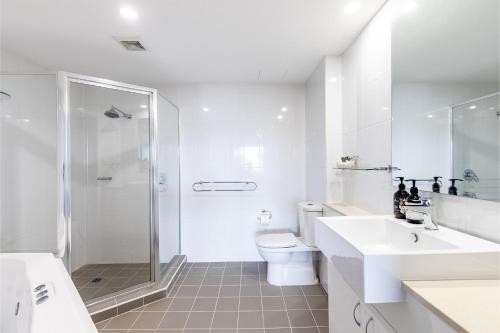 a white bathroom with a shower and a toilet at Footprints 1 in Fingal Bay