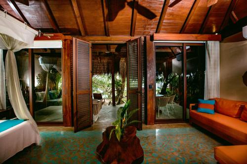 a room with a bed and a couch and glass doors at Hotel Rancho Encantado in Bacalar