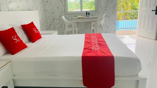 a bedroom with a white bed with red pillows at Sena Gladyz Suites in Panabo