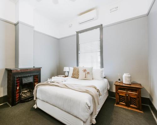 a white bedroom with a bed and a fireplace at Federal Hotel Mudgee in Mudgee