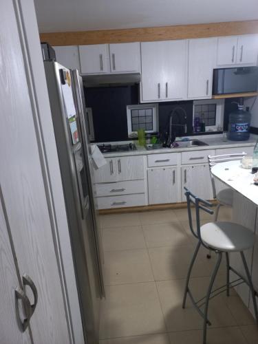 La cuisine est équipée de placards blancs, d'une chaise et d'un réfrigérateur. dans l'établissement Casa MA, à San Luis Potosí