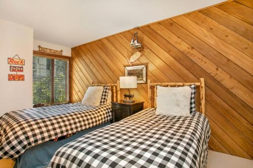 two beds in a room with wood paneling at 125 Ridgepoint Townhomes Townhouse in Avon