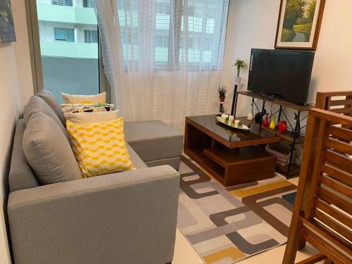 a living room with a couch and a television at The Residences at Commonwealth by Century in Manila