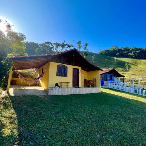 una pequeña casa amarilla con un gran patio en Chales Mirante Pedra Selada, en Visconde De Maua