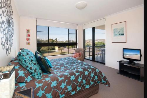a bedroom with a bed and a television and a balcony at The Dunes 17 38 Marine Drive fabulous unit with pool tennis court in Fingal Bay