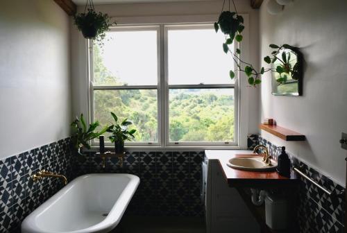 baño con bañera, lavabo y ventana en Mesa Bus - Deluxe Byron Hinterland Eco Stay en Rosebank