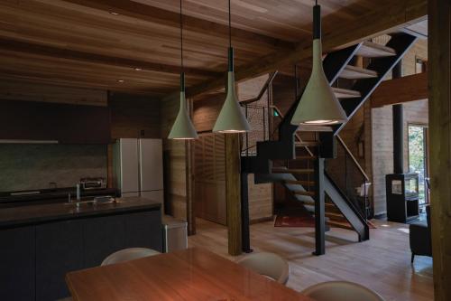 a kitchen and dining room with a table and a staircase at Hygge Chalet Hakuba in Hakuba