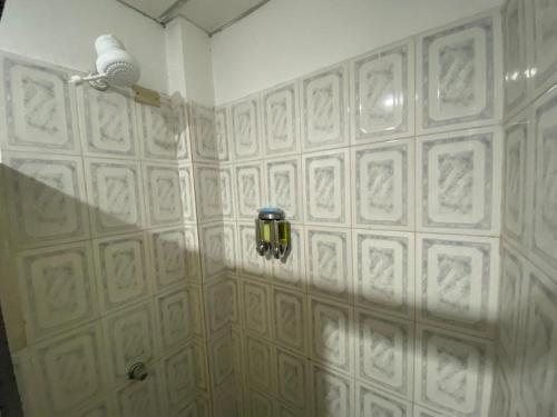 un baño con una pared de azulejos blancos con una luz en él en SUITES FAMILIAR, en Guayaquil