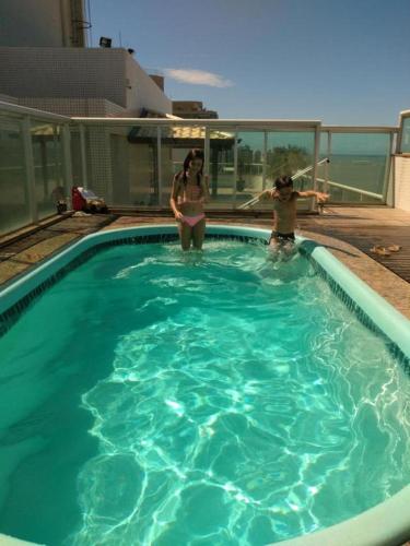 two women are standing in a swimming pool at FLAT frente Mar Green Diamond in Vila Velha