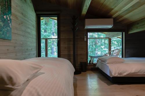 a bedroom with two beds in a room with windows at Hygge Chalet Hakuba in Hakuba