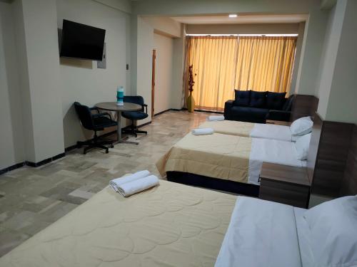 a hotel room with two beds and a couch and a table at OCEANIk SUITES & HOTEL in Guayaquil