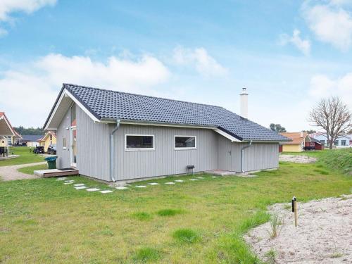 a gray house with a roof on a grass field at 8 person holiday home in Gro enbrode in Großenbrode