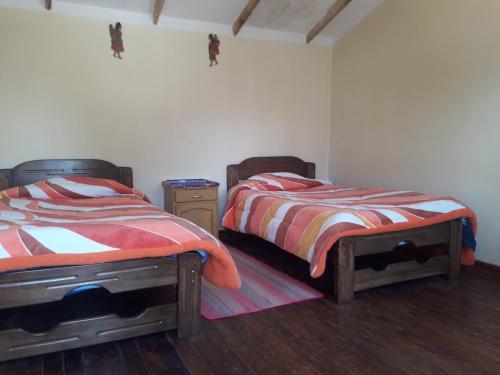 two twin beds in a room with wooden floors at Inka Wasi in Isla de Sol