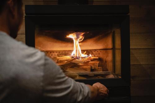 a person is standing in front of a fireplace at Hygge Chalet Hakuba in Hakuba