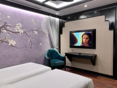 a bedroom with two beds and a tv and a desk at Hotel du Monde Classic in Hanoi