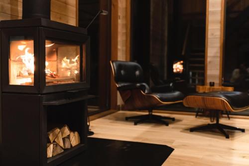 a living room with a fireplace and chairs at Hygge Chalet Hakuba in Hakuba
