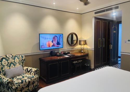 a bedroom with a bed and a chair and a television at Hotel du Monde Art in Hanoi