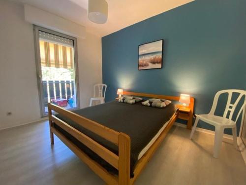 une chambre avec un grand lit avec un mur bleu dans l'établissement Appartement T2 rénové pour 4 pers, au pied de la plage avec 2 balcons et parking privé, St Georges - FR-1-494-135, à Saint-Georges-de-Didonne