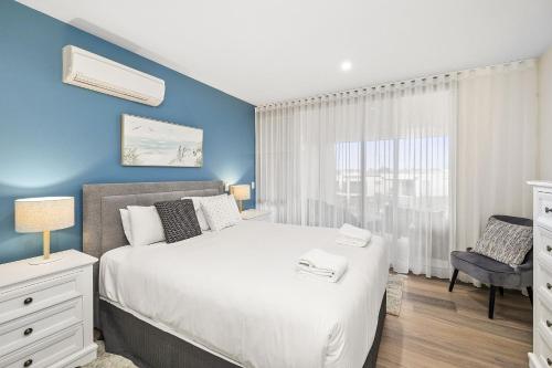 a bedroom with a white bed and a blue wall at Resort Penthouse 305 in Torquay