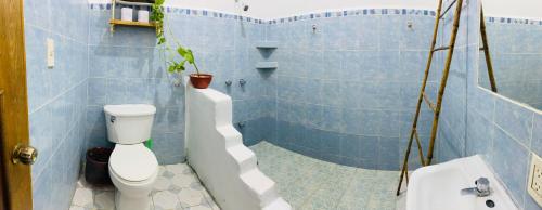 a blue tiled bathroom with a toilet and a plant at Casa Karma in Puerto Escondido