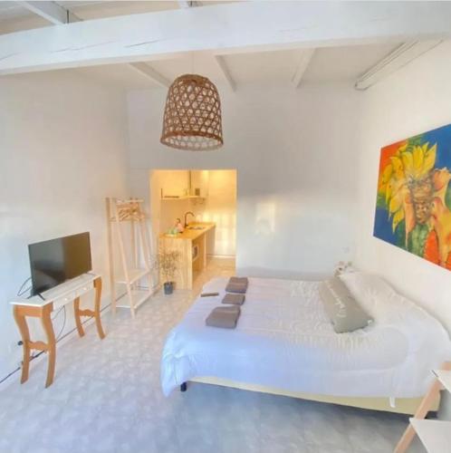 a white bedroom with a large bed and a desk at La Puerta Azul in Tandil