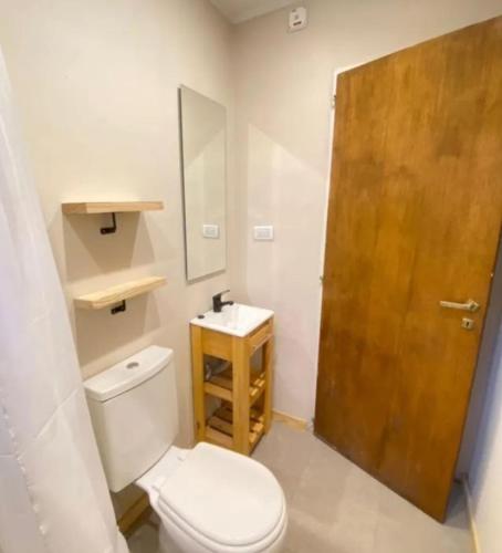 a bathroom with a toilet and a wooden door at La Puerta Azul in Tandil
