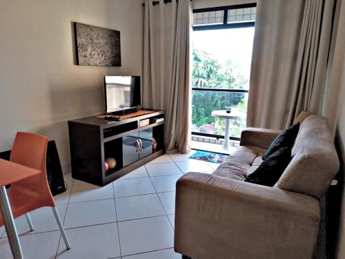 ein Wohnzimmer mit einem Sofa und einem TV in der Unterkunft Quadra da praia Ar-condicionado in São Vicente