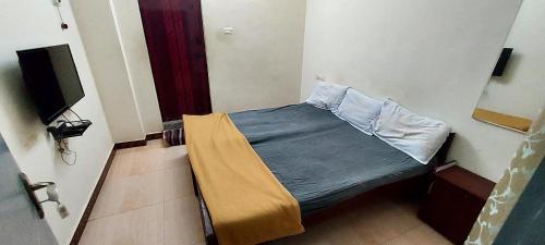 a bedroom with a bed with a blue blanket and a tv at Vijaya Rooms in Tiruchchirāppalli