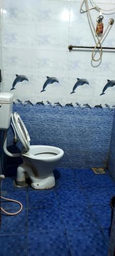 a bathroom with a toilet and dolphins on the wall at Vijaya Rooms in Tiruchchirāppalli