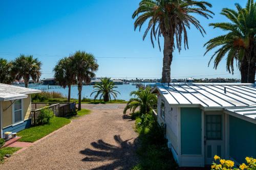 una casa con palmeras y un cuerpo de agua en Sangria Sunset, en Rockport