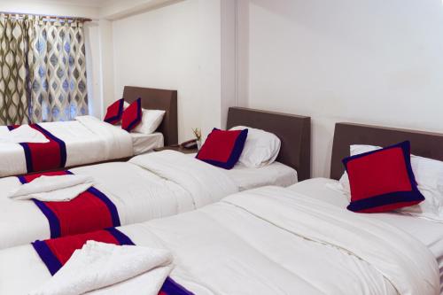 Habitación con 4 camas y almohadas rojas y azules. en Sweet Inn en Bhaktapur