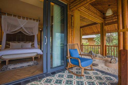 a bedroom with a bed and a chair on a porch at Le Champ Tu Le Resort Hot Spring & Spa in Yen Bai